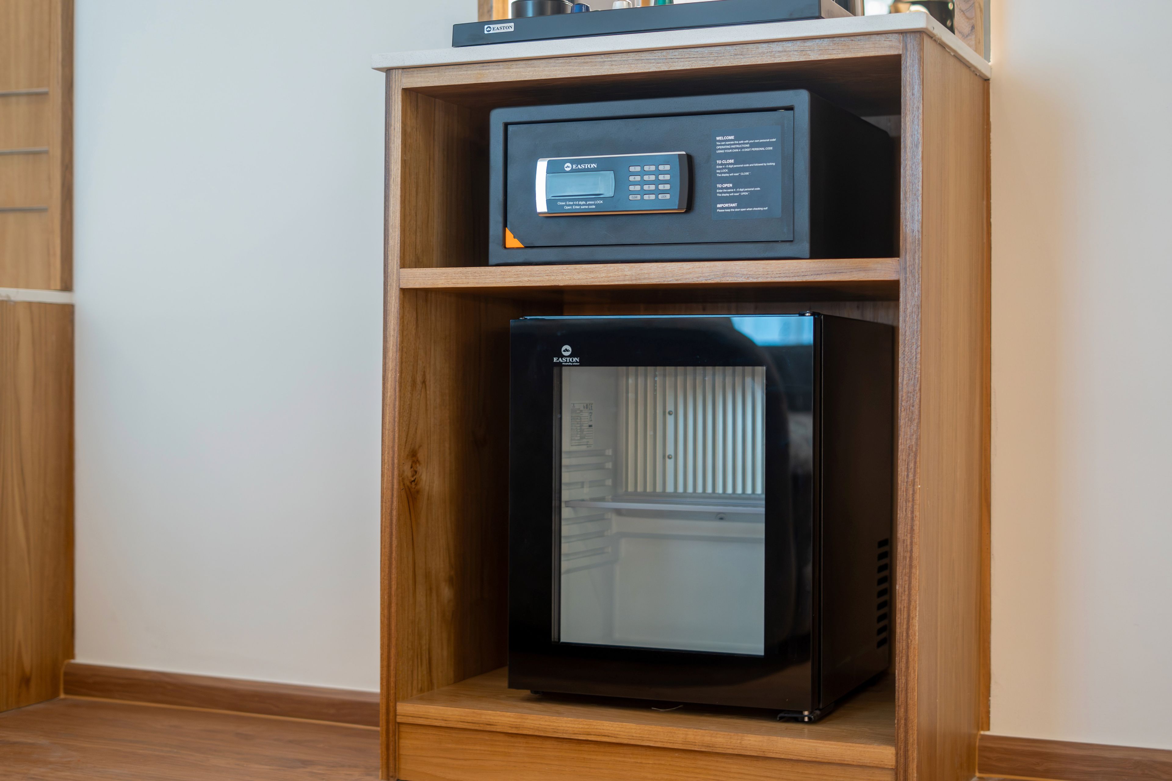 A black refrigerator with a digital control panel on top, placed inside a wooden cabinet.