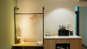 A kitchenette with a microwave, a hanging clothes rack, a basket with a plant, and a small table with towels. - Studio Near Ben Thanh Market - D2 Apt by D Haus (Thành phố Hồ Chí Minh)