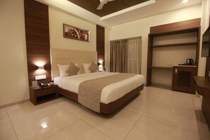 Habitación de hotel con una cama grande, mesitas de noche, un televisor de pantalla plana, un armario y un ventilador de techo.