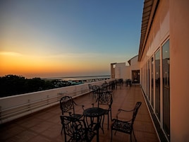 Una terraza con mesas al aire libre y vistas al atardecer.