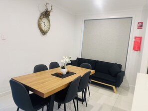 Ein Konferenzraum mit einem Holztisch, schwarzen Stühlen, einer weißen Orchidee, einer Zieruhr, einem schwarzen Sofa und einem Schild für eine Feuerdecke.