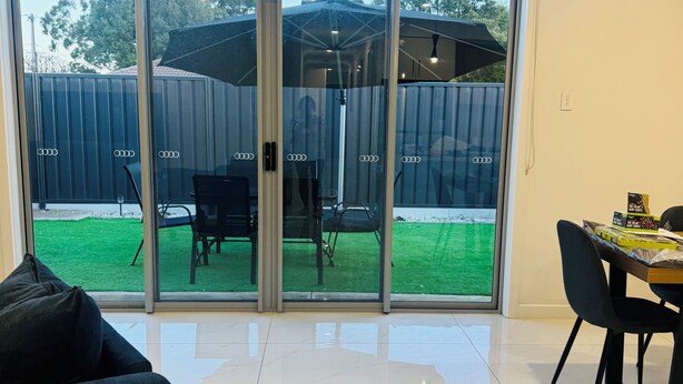 Een moderne woonkamer met een schuifpui naar een achtertuin met een patio tafel en stoelen.
