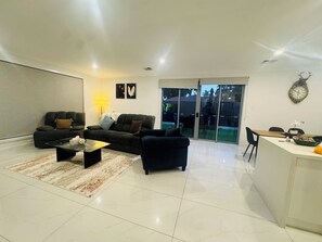 Ein modernes Wohnzimmer mit einer Couch, einem Couchtisch und einem Essbereich mit Tisch und Stühlen.