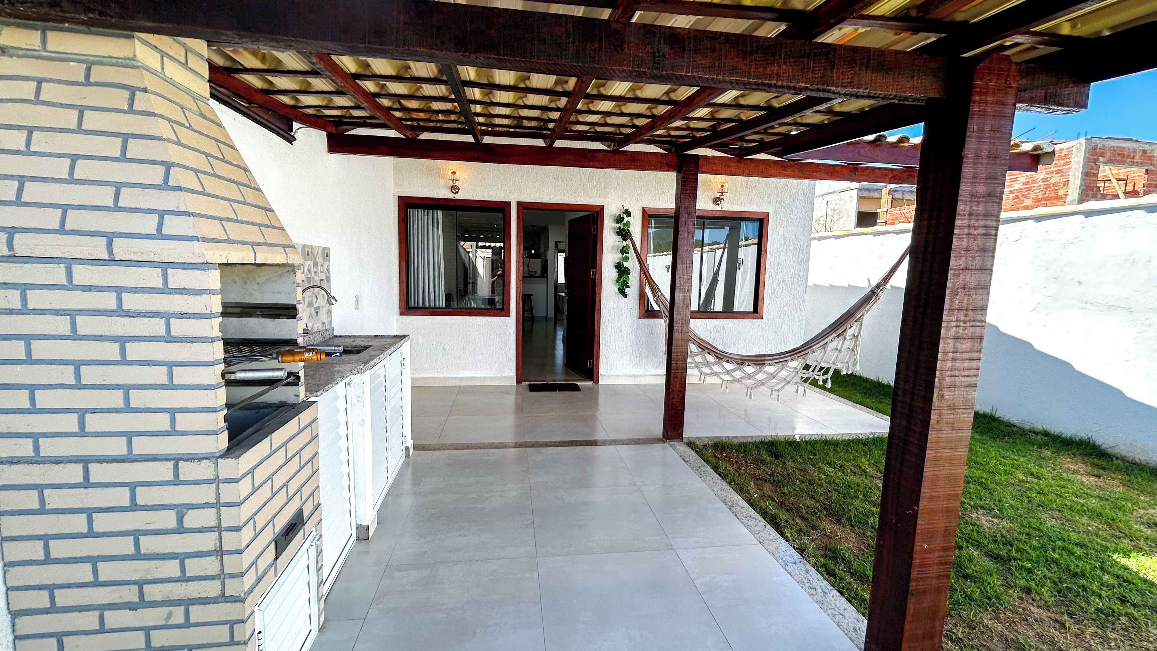 Un patio techado con una parrilla, una hamaca y vistas a una zona residencial.