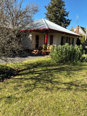 A house with a red porch, a chimney, and a well-maintained lawn.