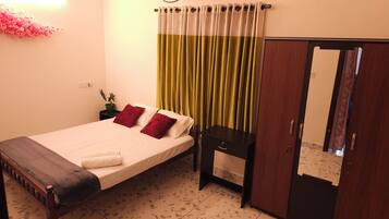 Habitación de hotel con cama, mesita de noche, armario y cortina verde.