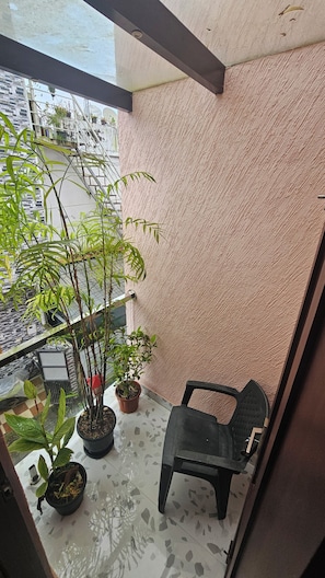 A balcony with a potted plant, a chair, and a textured wall. - Bethany Homestay (Kochi)