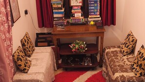 A cozy living room with a fireplace, a clock, and a bookshelf filled with books.