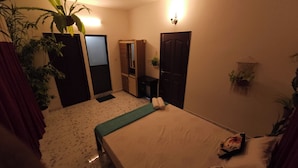A room with a bed, a mirror, a door, and a potted plant.