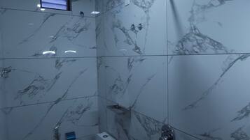Une salle de bain avec des murs en marbre, une douche et des toilettes.
