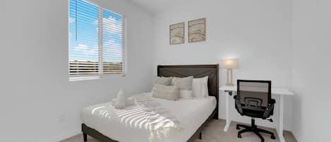 Un dormitorio con cama, escritorio y silla.