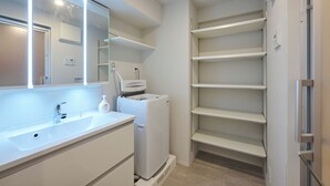 Un baño moderno con lavamanos blanco, espejo y calefacción integrada.