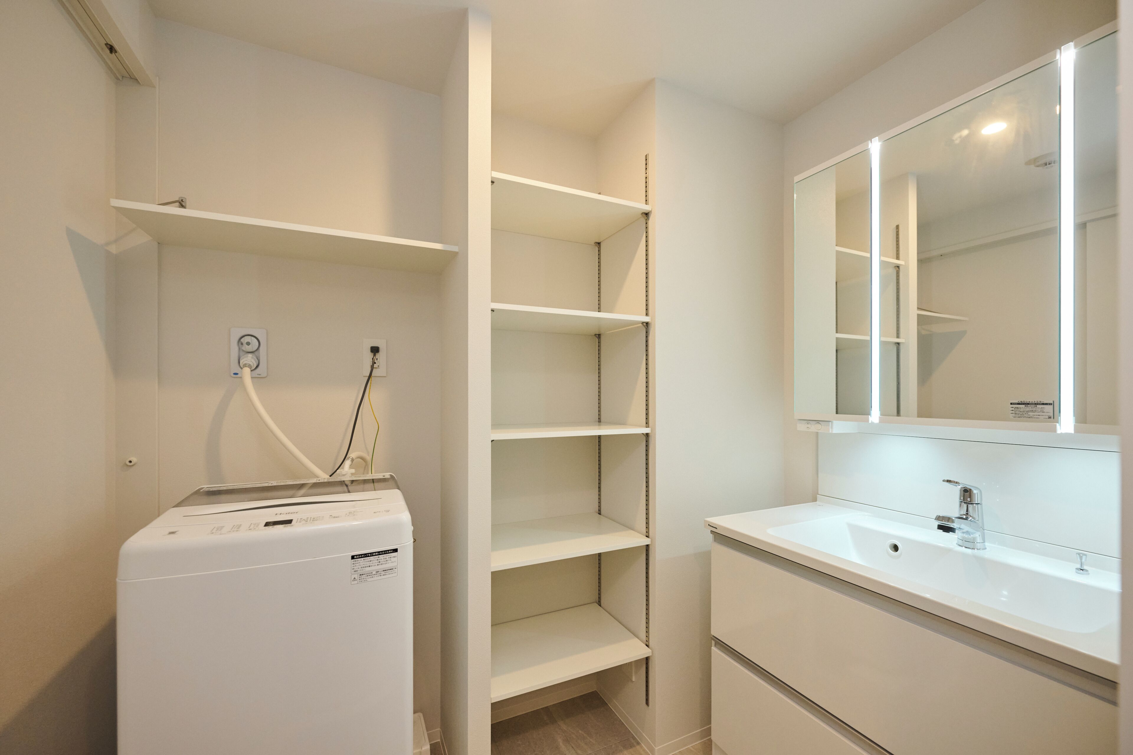 A modern bathroom with a white washing machine, a sink, and a mirror.