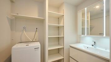 A modern bathroom with a white washing machine, a sink, and a mirror.