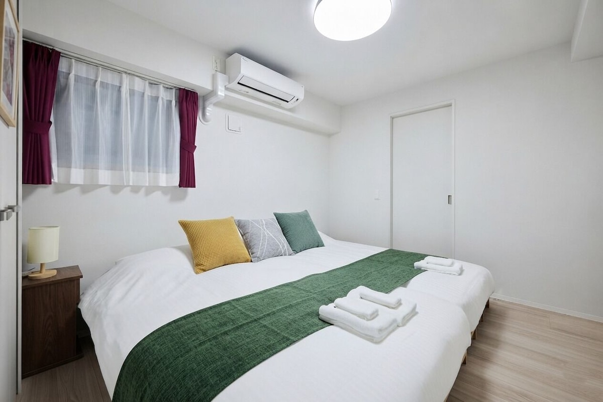 Ein Hotelzimmer mit Bett, Nachttisch mit Lampe, Klimaanlage und Tür.
