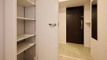 A room with a white door, a dark wooden door, and a white wall with a light switch.
