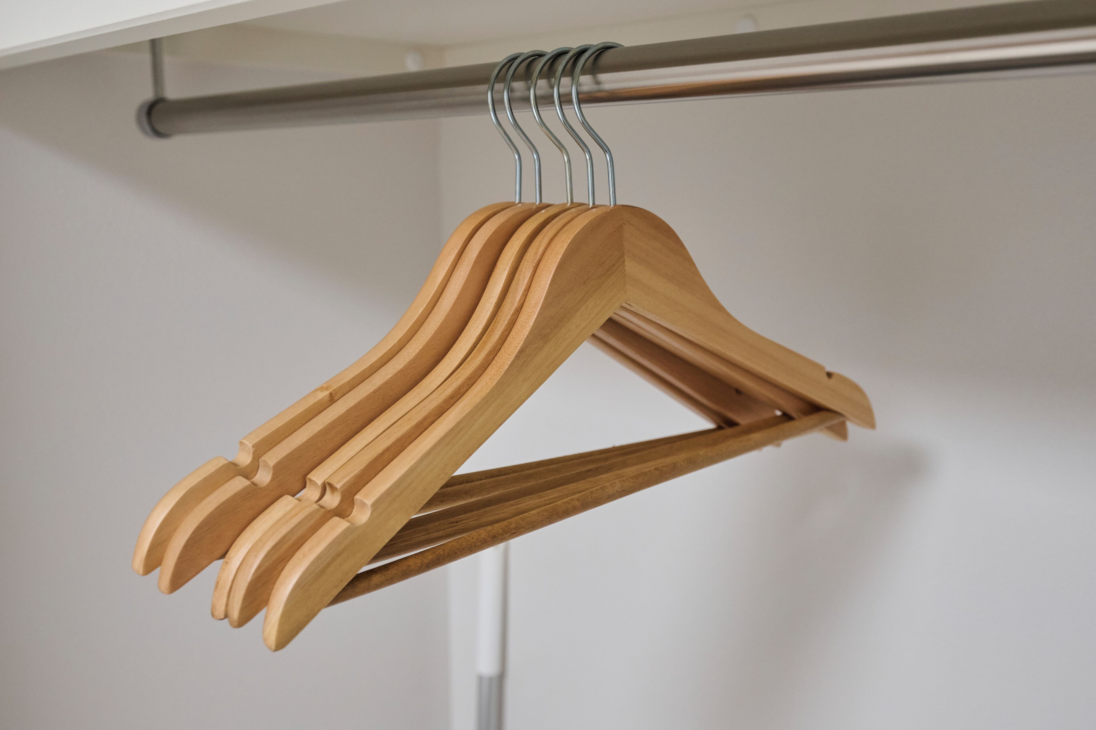 A wooden hanger with a metal hook attached to a metal rod.