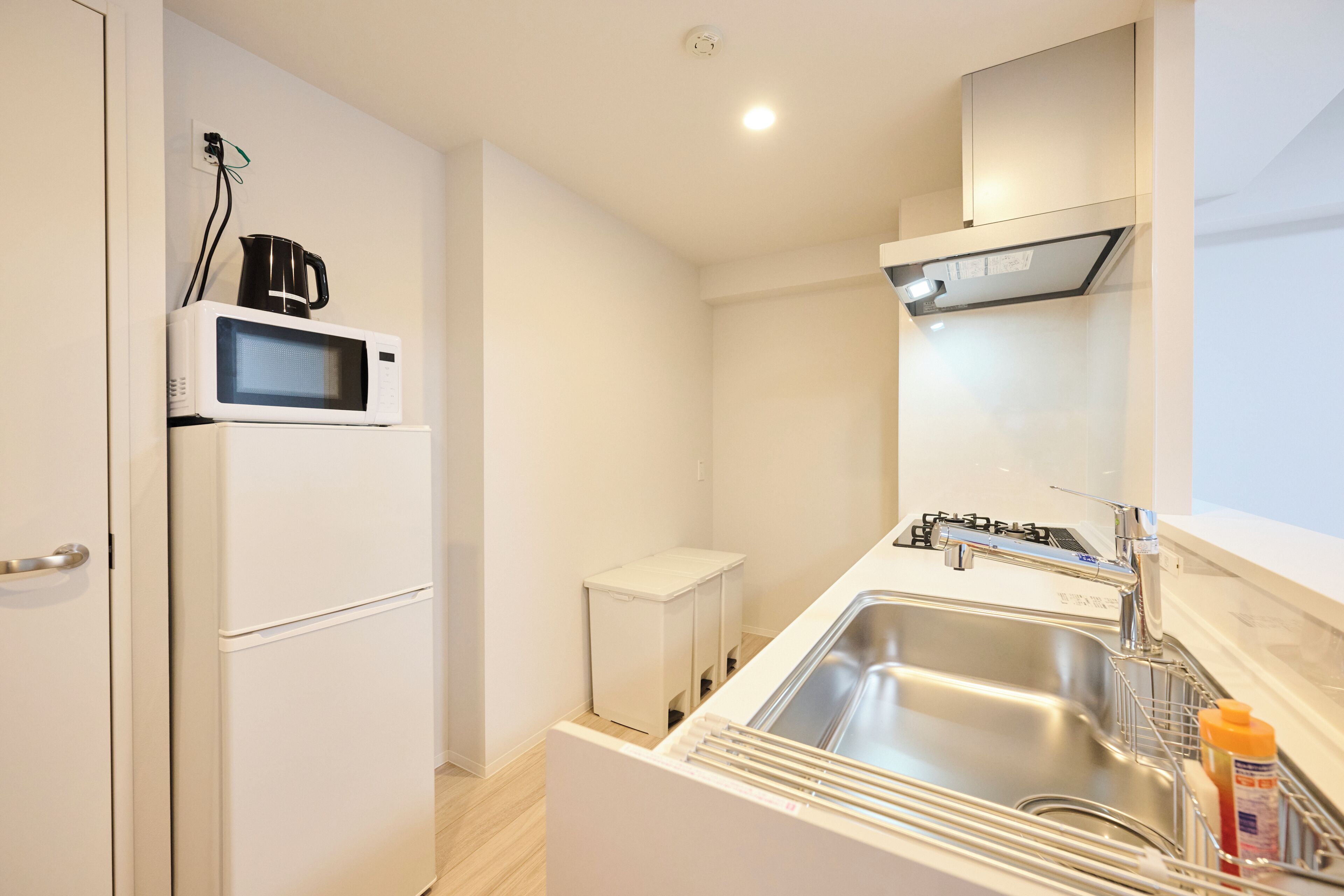 A compact kitchenette with a microwave, a small refrigerator, a sink, and a stove.