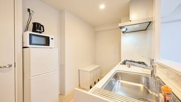 A compact kitchenette with a microwave, a small refrigerator, a sink, and a stove.
