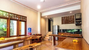 A spacious kitchen with wooden benches, a water dispenser, and a refrigerator.