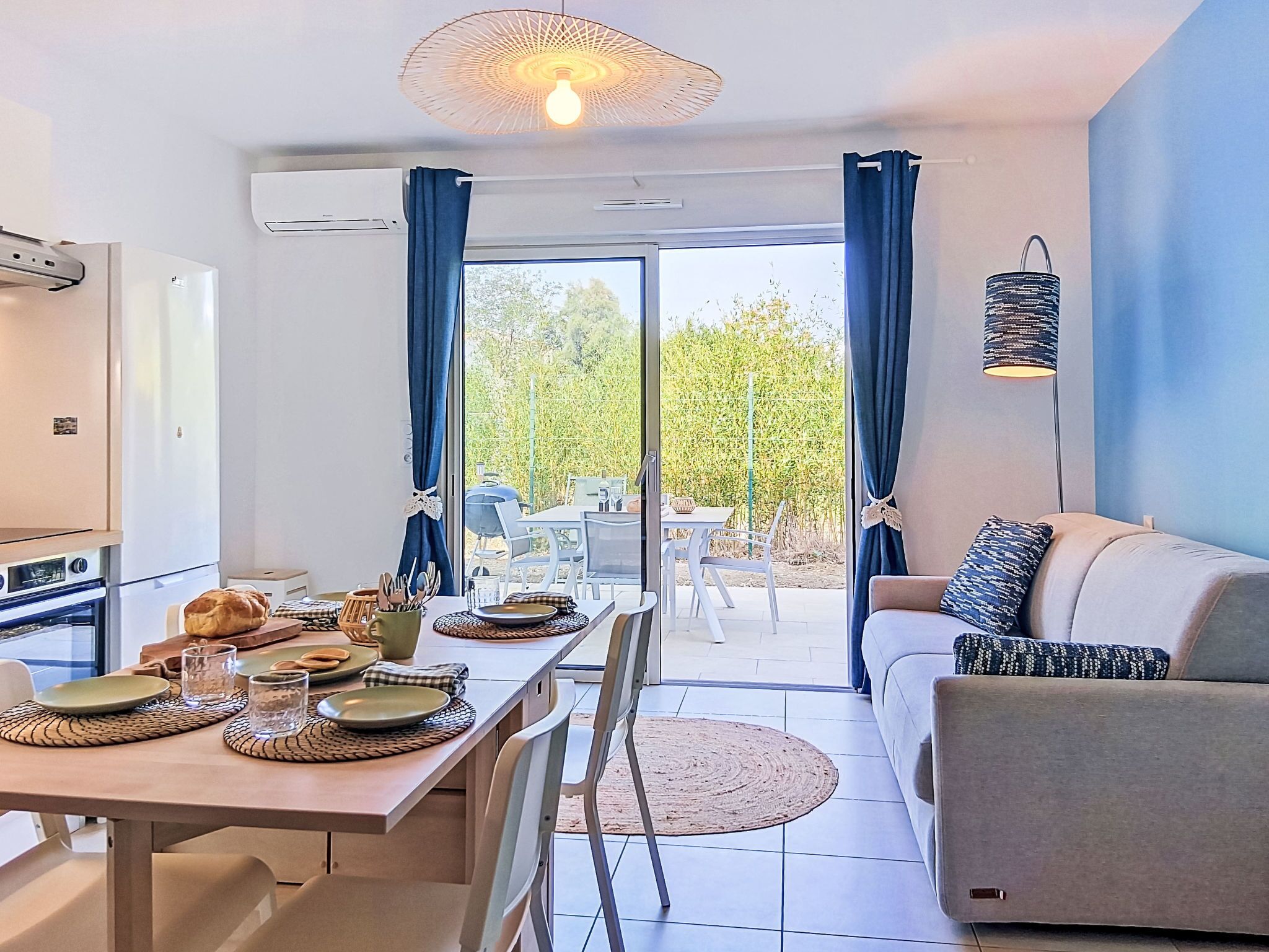 A modern kitchen with a dining area, a sofa, and a view of the outdoors.