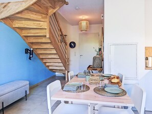 A dining area with a wooden staircase, a clock, and a dining table set with plates and glasses. - Les Bains d'Oléron 2 by Interhome (Ile d'Oléron)