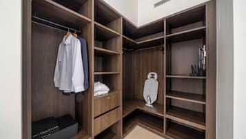 Un vestidor amplio con varios estantes y espacio para colgar ropa, un zapatero y una plancha pequeña.