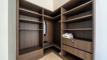 Ein begehbarer Kleiderschrank mit mehreren Holzböden und einer Kleiderstange, ausgestattet mit einer neutralen Farbgestaltung und einem gefliesten Boden.