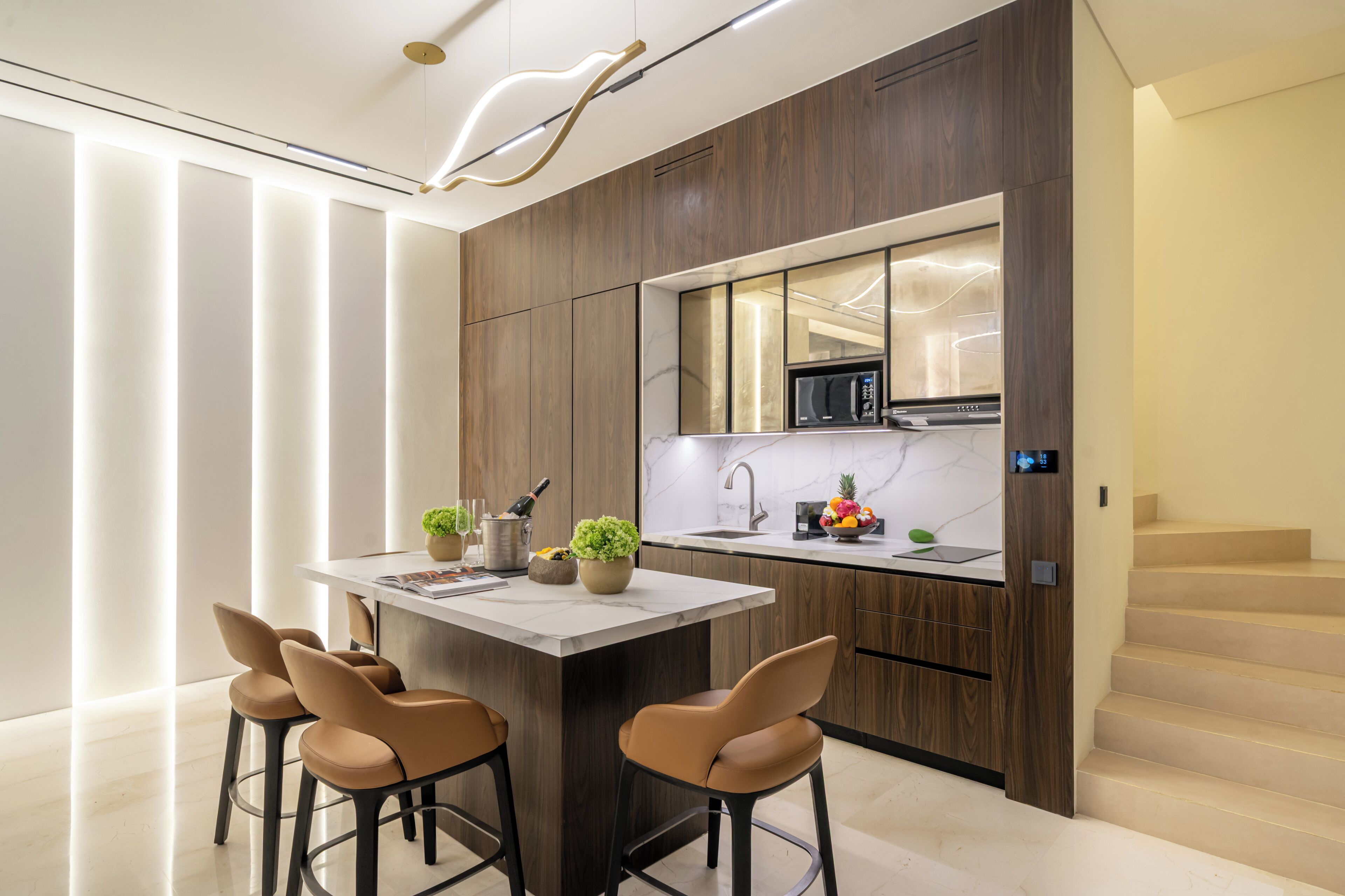 A modern kitchen with a central island, wooden cabinetry, and a built-in microwave.