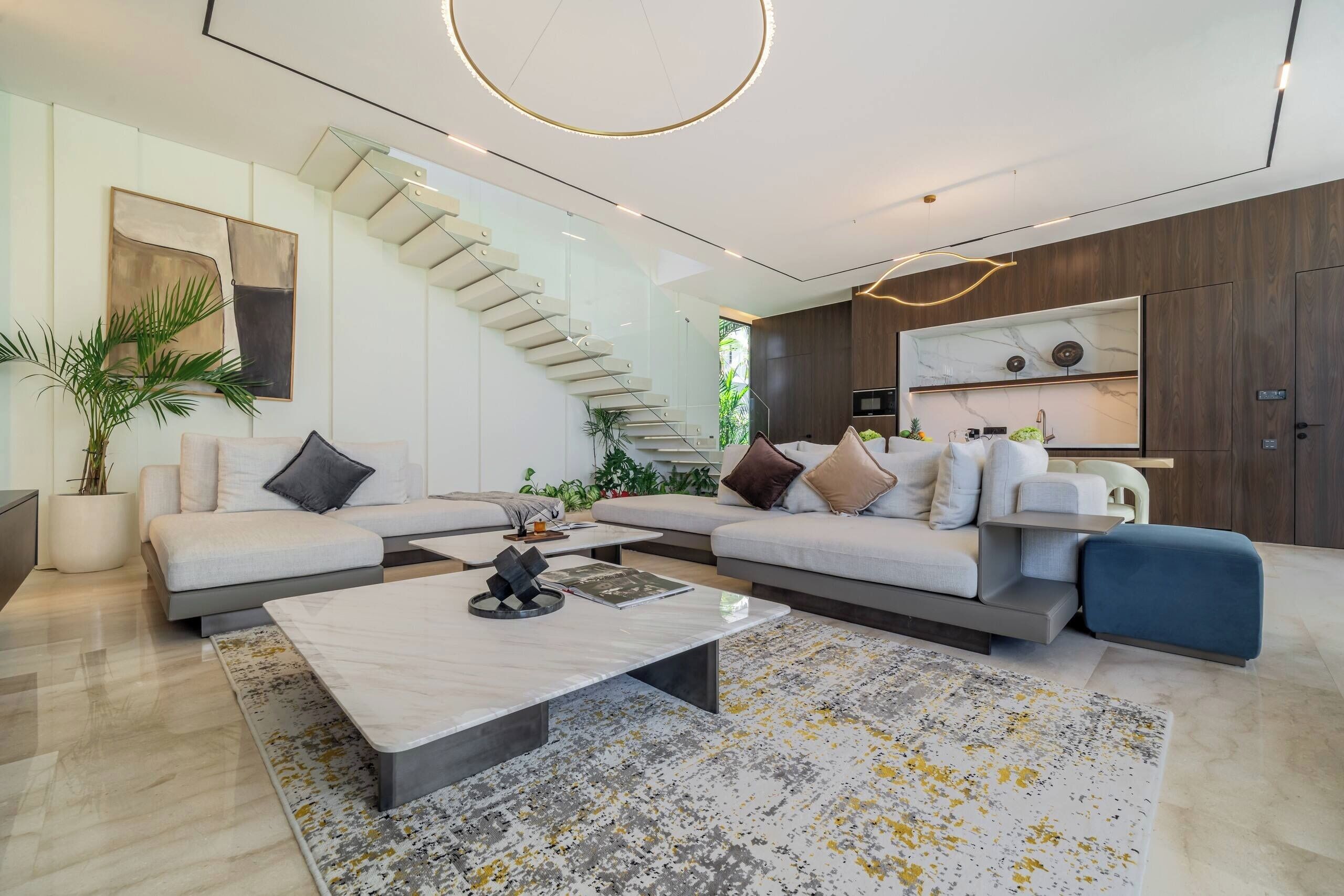 A modern living room with a sectional sofa, a coffee table, and a staircase.