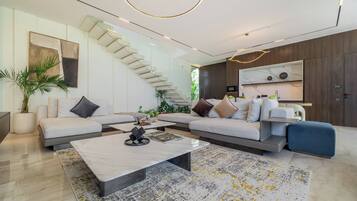 A modern living room with a sectional sofa, a coffee table, and a staircase.