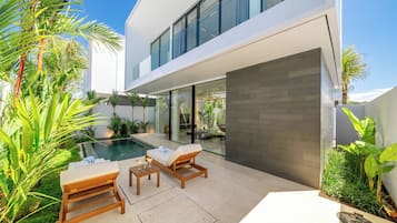 Une maison moderne dotée d’une piscine, de mobilier d’extérieur et d’une végétation luxuriante.