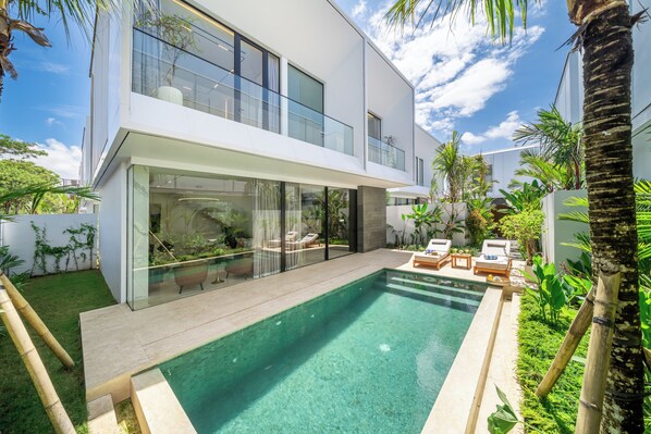 Une maison moderne à deux étages, dotée d’un patio entièrement vitré et d’une piscine.