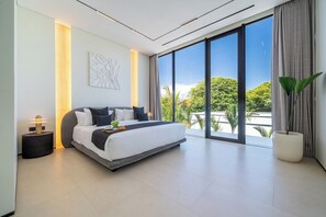A modern bedroom with a large bed, a bedside table, a nightstand, a wall-mounted light, and a large window with a view of greenery.