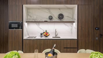 Une cuisine moderne avec un revêtement mural en marbre, un four encastré et un coin repas avec une table mise pour deux personnes.