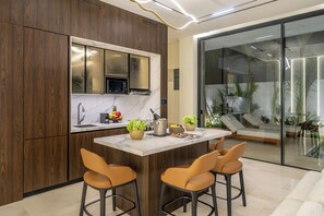 A modern kitchen with a central island, wooden cabinets, and a built-in microwave.