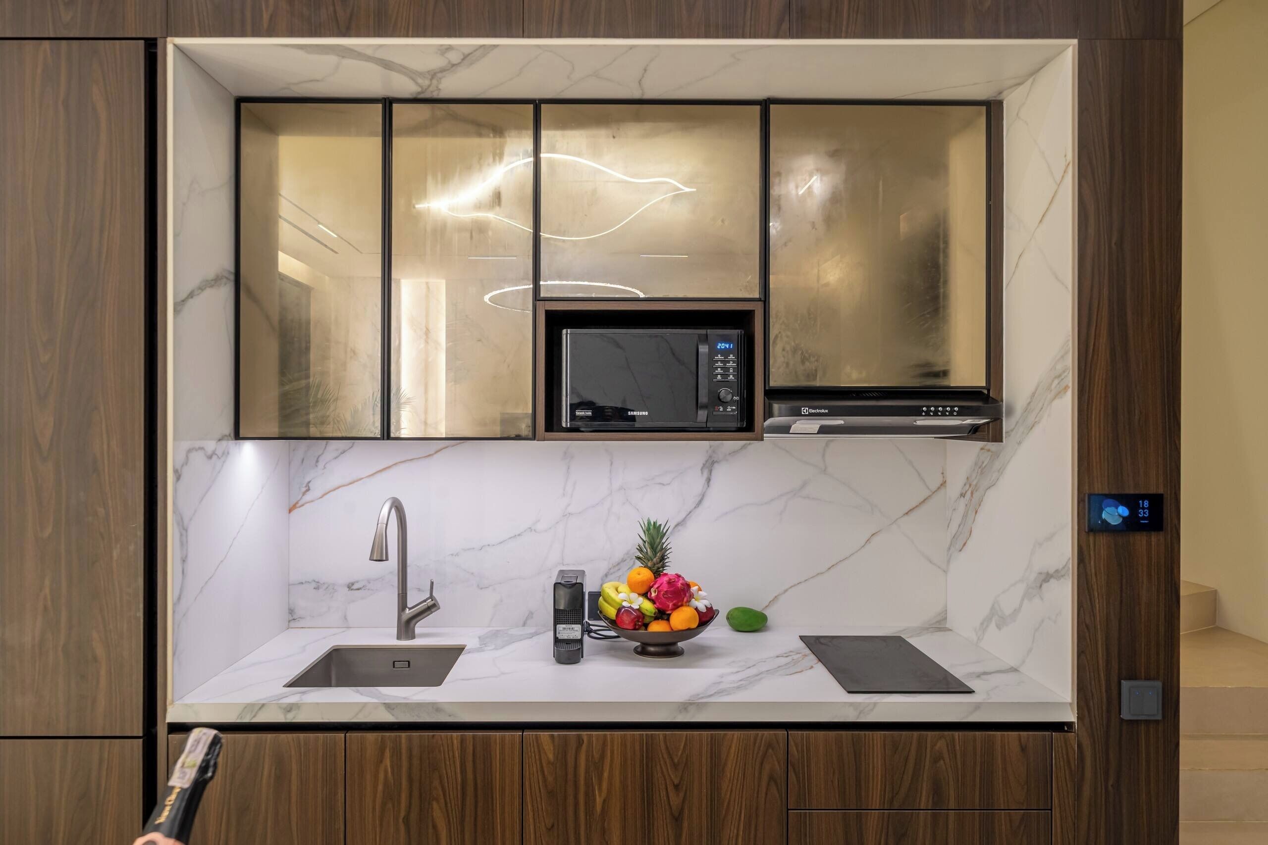 Una cocina moderna con microondas integrado, un lavaplatos de acero inoxidable y un frutero en la encimera.
