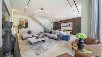 A modern living room with a staircase, a kitchen area, and a dining space.