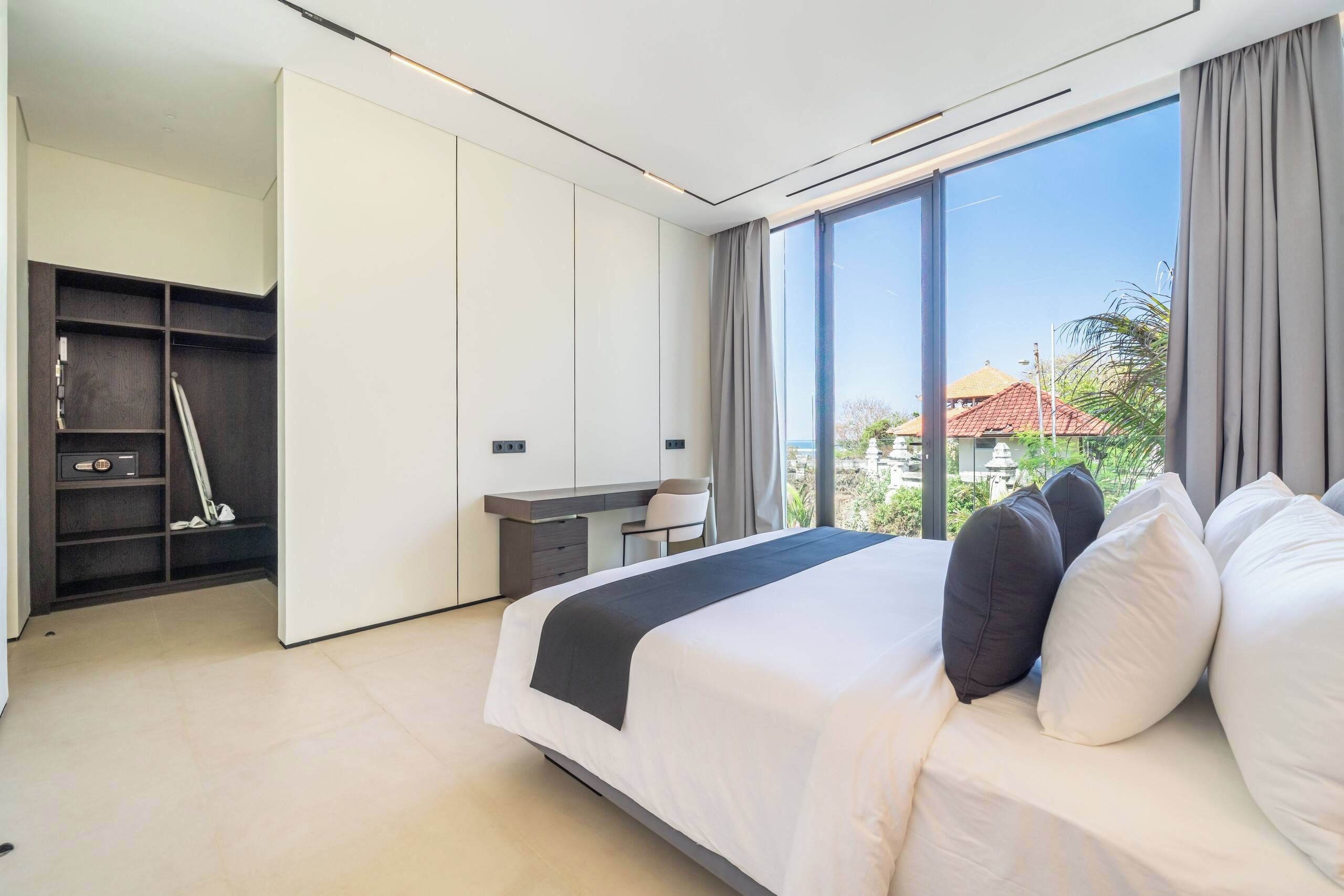 A modern bedroom with a bed, a desk, and a wardrobe.