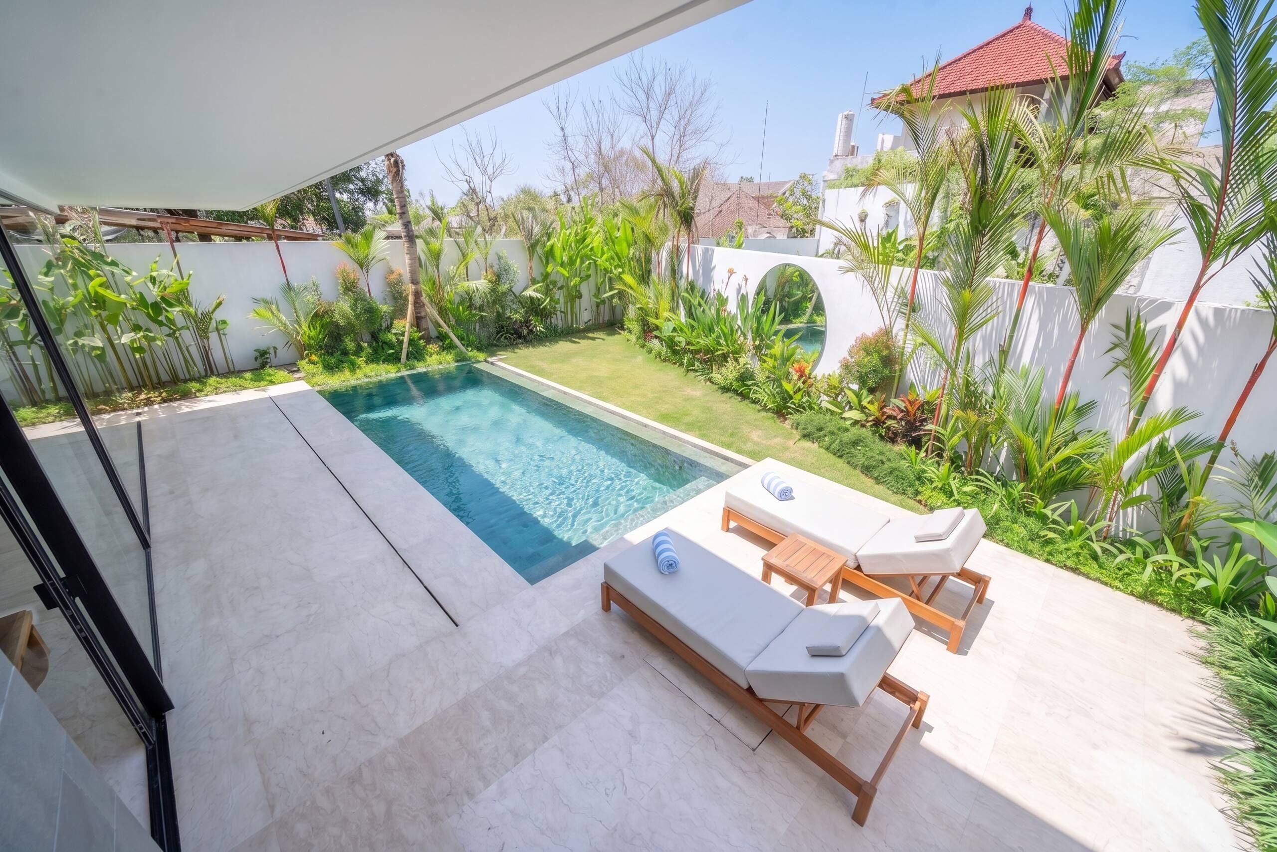 Una piscina con sillas de descanso y un jardín.