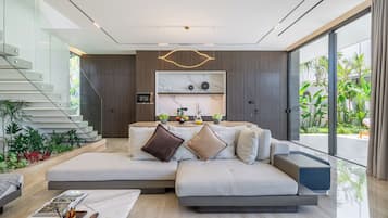 Un salon moderne avec un canapé d’angle, une table basse et un coin repas doté d’un îlot de cuisine.