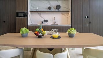 Een moderne keuken met een marmeren achterwand, houten kastjes en een eettafel met stoelen.