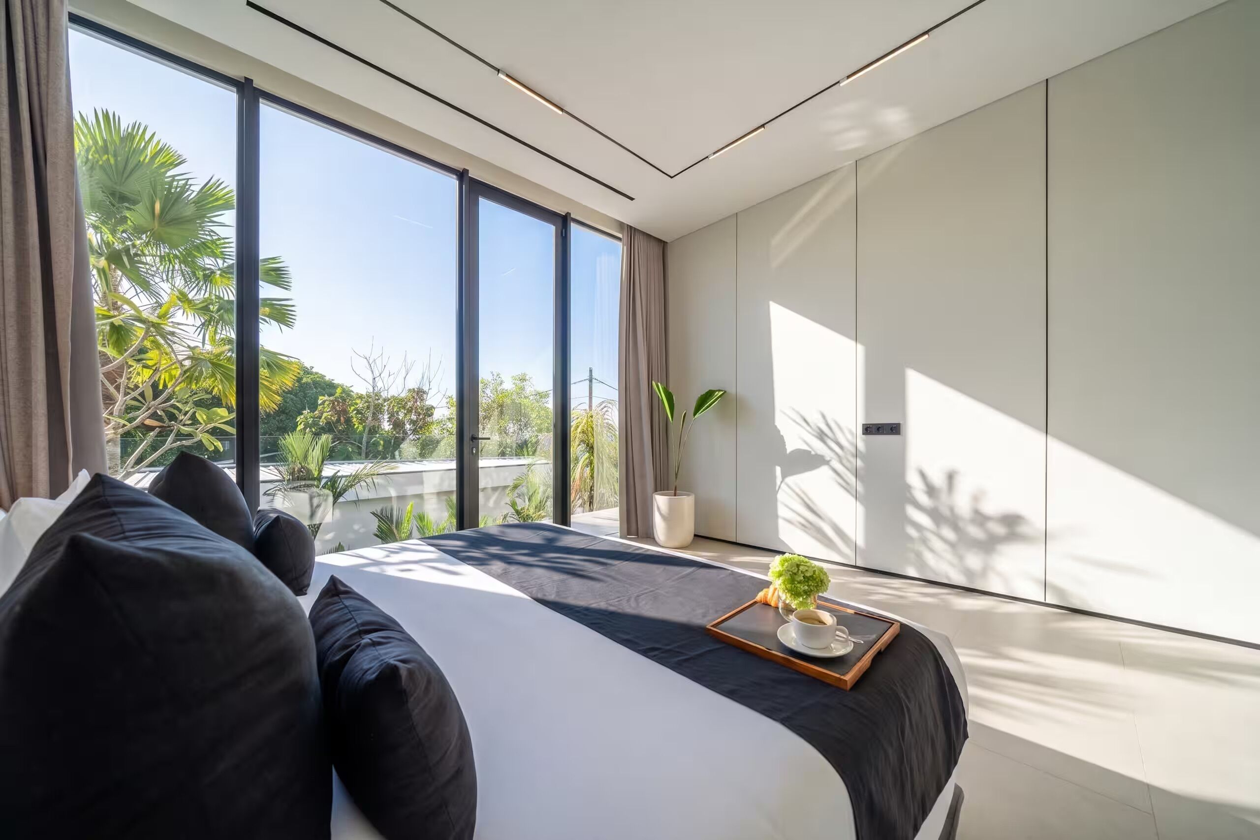 Ein modernes Schlafzimmer mit einem großen Bett und Blick auf Grünfläche, im minimalistischen Stil.