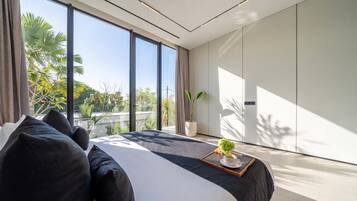 Ein modernes Schlafzimmer mit einem großen Bett und Blick auf Grünfläche, im minimalistischen Stil.