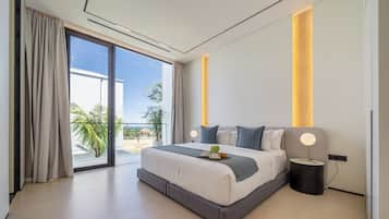 A modern bedroom with a large bed, a bedside table with a lamp, and a view of the outdoors.
