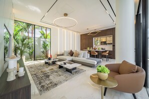 A modern living room with a sofa, coffee table, and a dining area with chairs.