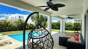 Ein überdachter Außenbereich mit Pool, Deckenventilator und Schaukelstuhl.