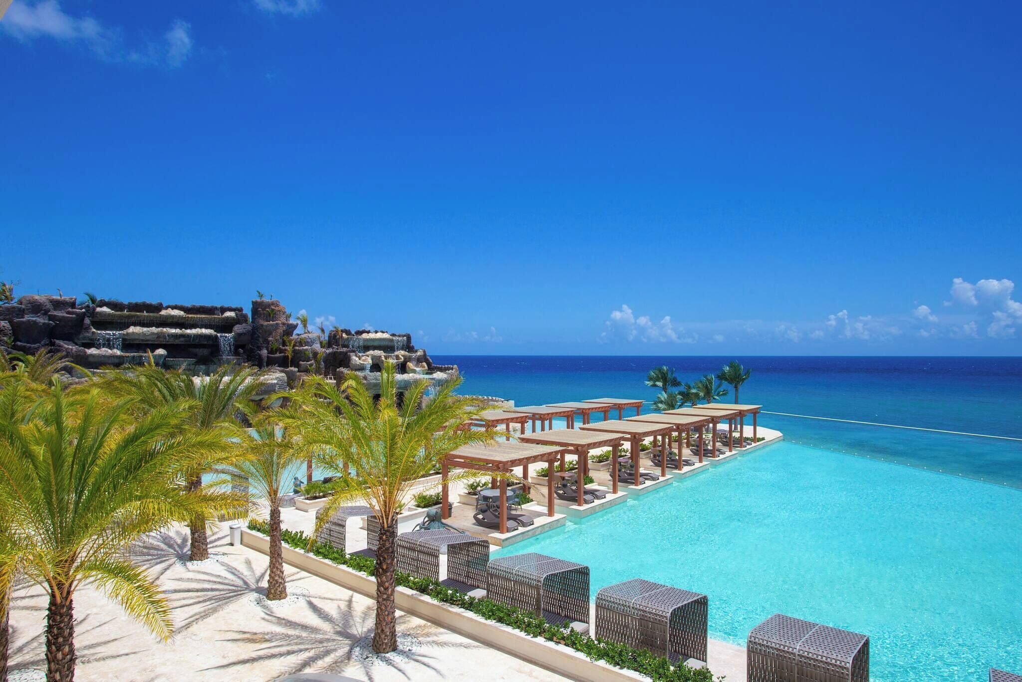 Un resort con piscina, palmeras y vista al océano.