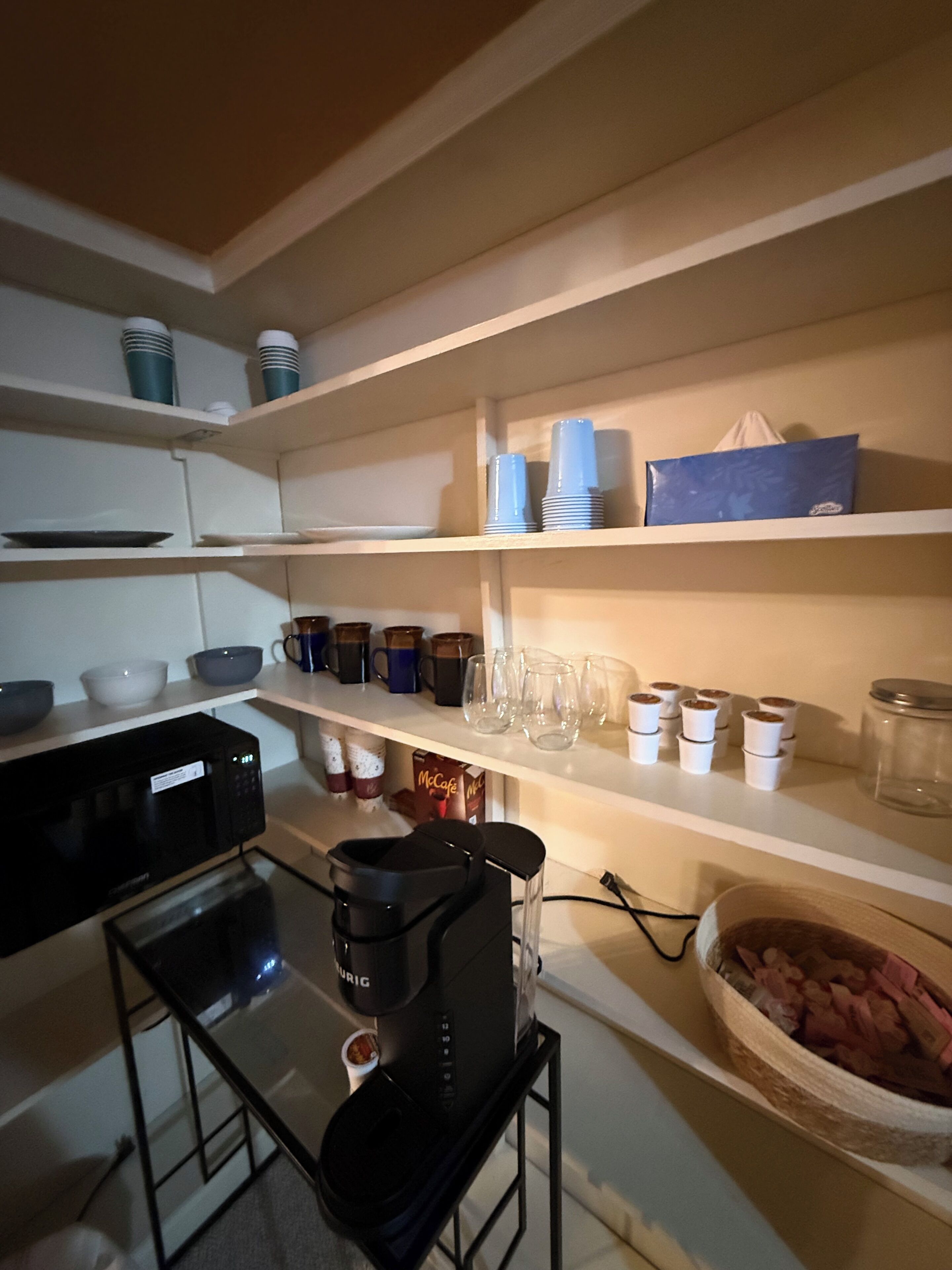 A kitchen with white shelves, a coffee maker, and various kitchenware.