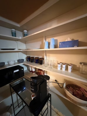 A kitchen with white shelves, a coffee maker, and various kitchenware.